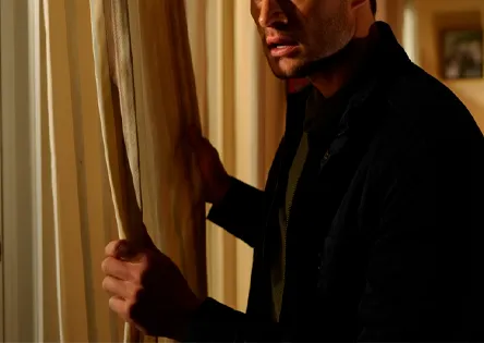 Мужчина осторожно выглядывает из-за штор
